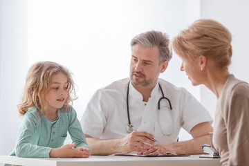 Helpful pediatrician and sick blond boy in a doctor's office