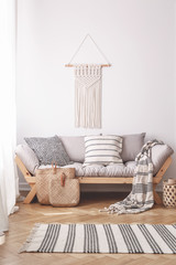 Bags on the floor of natural beige living room with settee and macrame on the wall