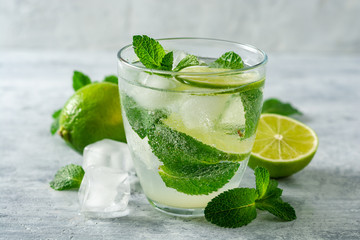 Fresh mojito cocktail with lime and mint in glass on concrete background. Cold refreshing drink. Selective focus.