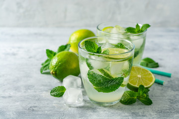 Fresh mojito cocktail with lime and mint in glass on concrete background. Cold refreshing drink. Selective focus.