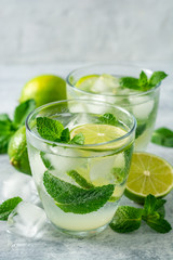 Fresh mojito cocktail with lime and mint in glass on concrete background. Cold refreshing drink. Selective focus.