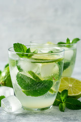 Fresh mojito cocktail with lime and mint in glass on concrete background. Cold refreshing drink. Selective focus.