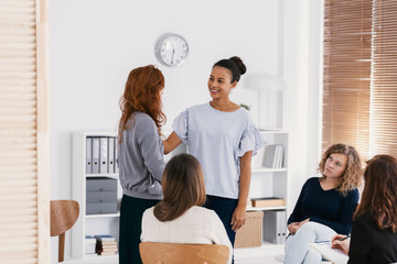 Redhead woman supporting sad friend during psychotherapy group meeting