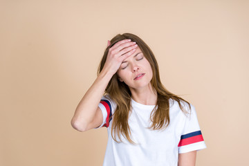 Front view of tired adult girl with closed eyes touching forehead
