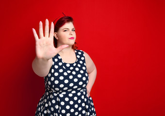 Serious young caucasian woman showing stop gesture with her hand.