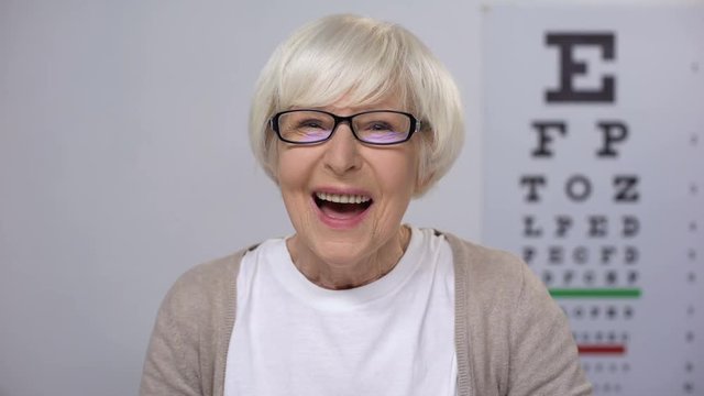 Lady retiree putting on spectacles and focusing vision, appointment by optician