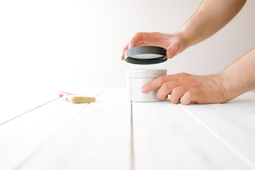 The man unscrews the paint can. The concept of DIY and renovation of new things. A man tinkering at home, working with wood.