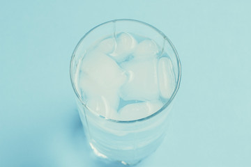 Refreshing cold Water with ice in a glass on a blue background. Concept of thirst, heat, refreshment in the summer. Flat lay, top view