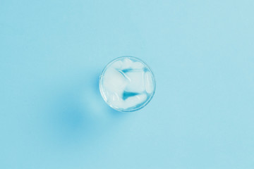 Refreshing cold Water with ice in a glass on a blue background. Concept of thirst, heat, refreshment in the summer. Flat lay, top view