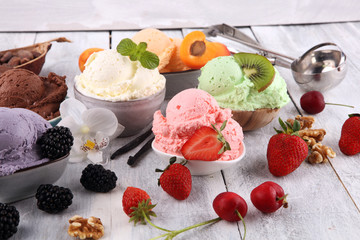 ice cream scoops of different colors and flavours with berries, nuts and fruits decoration on white background