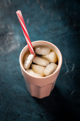 Iced coffee in a glass on a dark blue stone background. Concept cooling drink, thirst, summer, cola with ice. Flatlay, top view