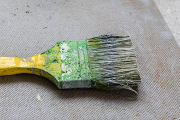 Dirty green paintbrush on a chipboard. House renovation