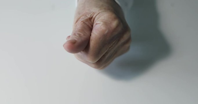 Close-up of old woman's hand with deep wrinkles showing Golden Bitcoin BTC coins.