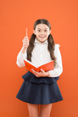 schoolgirl writing notes on orange background. get information form book. back to school. reading...