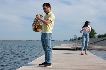 The guy playing the horn and the girl playing the flute on the lake © biggur