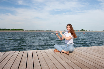 Fototapeta na wymiar A beautiful woman posing in beach while playing on a flute.