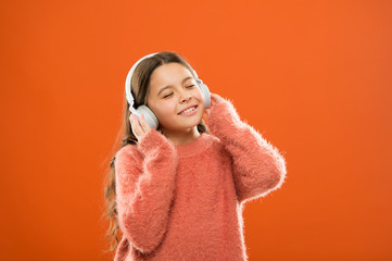 Girl cute little child wear headphones listen music. Kid listen music orange background. Recommended music based on initial interest. Best free music apps for your mobile device. Enjoy sound
