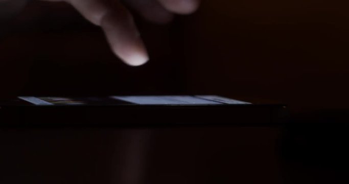 Scrolling through posts in social network on a smartphone at night - Internet addiction concept