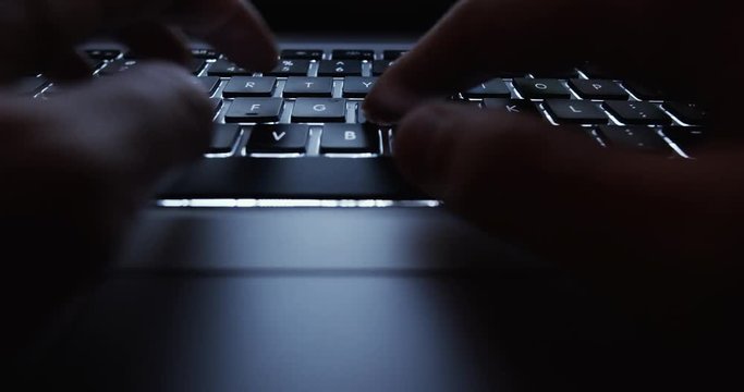 User typing on a laptop keyboard at night - hacker, it specialist, coding concept footage