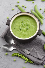 Fresh pea soup in bowl with spoons and napkin