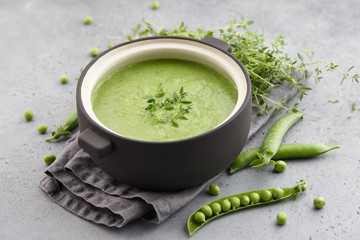 Fresh pea soup with thyme in ceramic pot