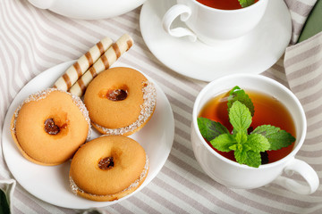 Two cups of hot tea with delicious cookies on white wooden table