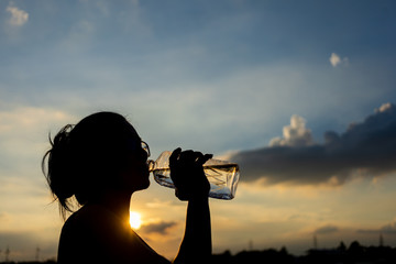Silhouetted of woman drinking water from the bottle