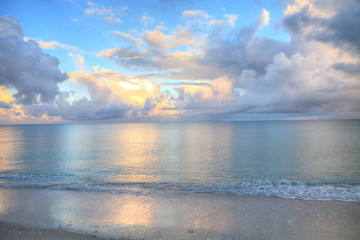 Ocean rolls in under puffy clouds on North Naples Beach at sunrise