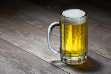 Delicious bright beer stein with frothy foam, poured fresh from the tap, on wooden table