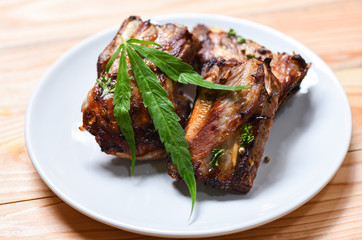 cannabis food with bbq pork ribs grilled with herbs spices served on white plate - Roasted barbecue pork spare rib and marijuana leaf