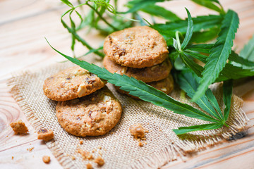 Cookies with cannabis leaf marijuana herb on sack wooden background - cannabis food snack for health