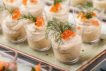 Delicious appetizers with red caviar, shrimp and cheese mousse in glass cups on banquet table....