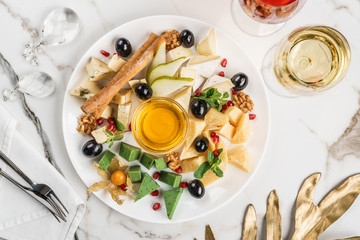Cheese plate, green cheese, brie cheese served with wine, bread sticks and honey over light marble background. Snacks and Wine appetizers set, top view, flat lay