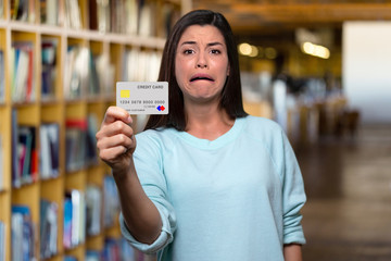 Struggling college student holding mockup bank credit card, in debt after paying for books and expensive tuition fees