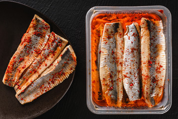Marinated fillet mackerel or fillet herring fish with spices packed in box on plate over slate...