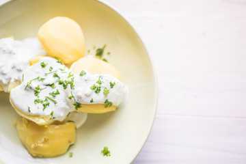 Delicious jacket potatoes. Cooked in water..Nice simple dish with sour cream. Everything on a green plate garnished with herbs.