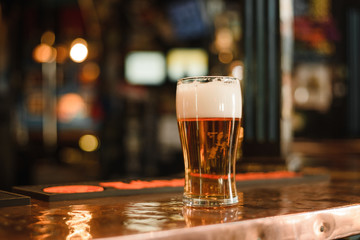 a glass of beer in a popular bar. Pint of foamy drink in a restaurant.