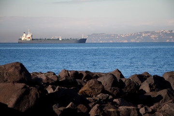 View of the huge sea liner from the rocky shore against the blue sky
