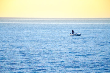 Unrecognizable man sailing on a boat with oars in the sea, a fisherman in a boat