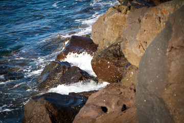 Top view from a rocky coast on a blue turquoise sea and waves
