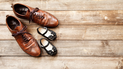Father and girl brown shoes on wooden background, fathers day