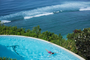 top view of the infinity pool and blue ocean. sunny hot day, tropics. woman swims underwater