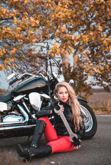 Fototapeta na wymiar Beautiful biker woman posing with motorcycle outdoors.