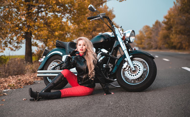 Obraz premium Beautiful biker woman posing with motorcycle outdoors.