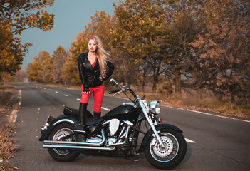 Plakat Beautiful biker woman posing with motorcycle on the road.