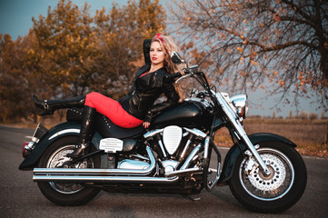 Plakat Beautiful biker woman posing with motorcycle on the road.