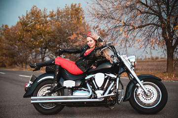 Fototapeta na wymiar Beautiful biker woman posing with motorcycle on the road.