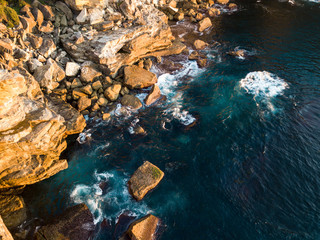 Small incoming wave at rocky coastline.