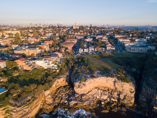 Aerial view of houses at Sydney coastline with Sydney CBD on the background.
