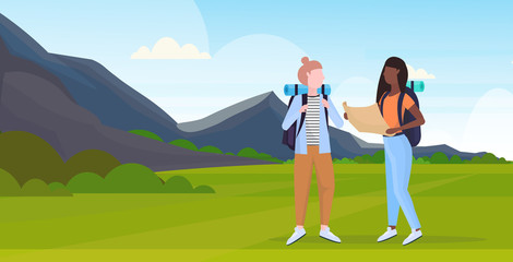 women hikers couple with backpack holding travel map mix race girls planning route hiking concept travelers on hike mountains landscape background full length horizontal flat